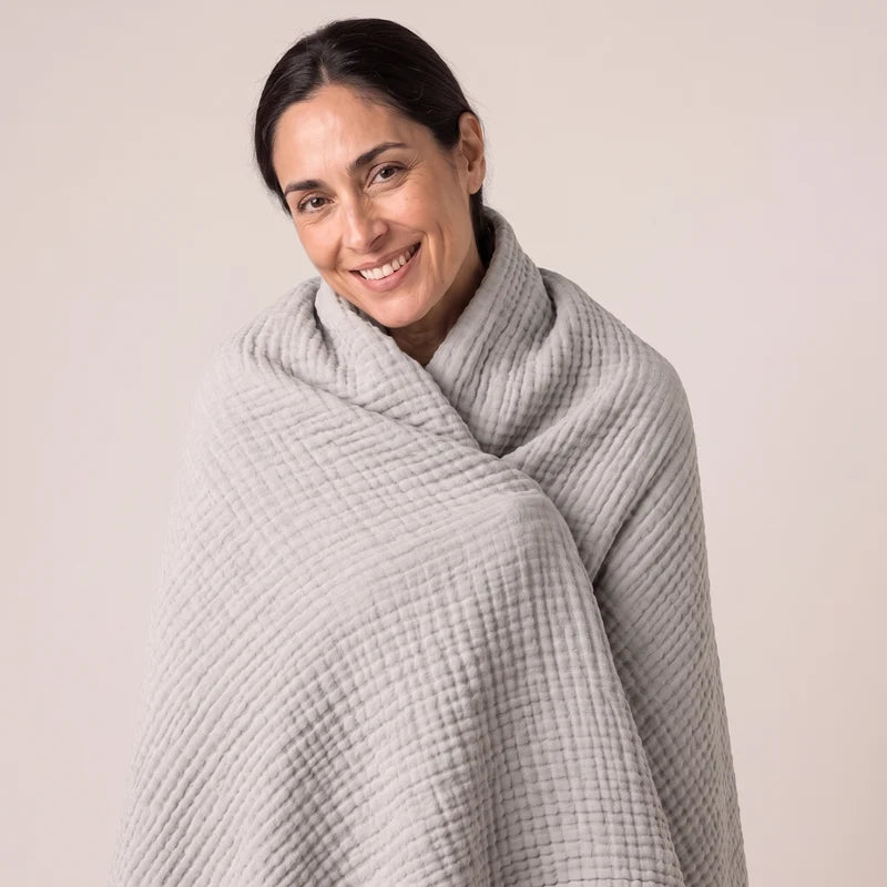 Woman wearing the Koforto Muslin Blanket in navy draped over both shoulders
